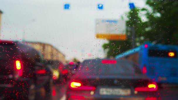 街中の渋滞の中に立って車のフロントガラスに雨滴に選択的な焦点を当てます 小さな滴は車のガラスに落ち ワイパーブレードによって運ばれます — ストック動画