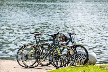 Moskova, Rusya. 14 Haziran 2020. Güneşli bir yaz gününde, gölün kıyısında birkaç bisiklet insan olmadan. Suyun yüzeyi güneşte parlar. Açık hava aktiviteleri kavramı.