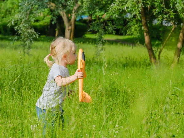 Fokus selektif pada seorang gadis pirang kecil dengan pesawat mainan oranye di tangannya — Stok Foto