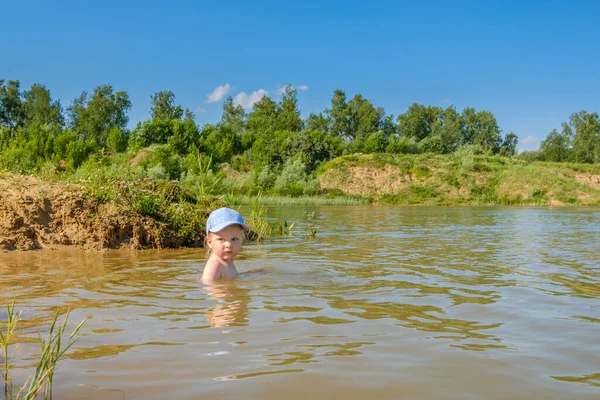 A menina loira em um gorro toma banho no rio e ri-se alegremente. Espaço de cópia . — Fotografia de Stock