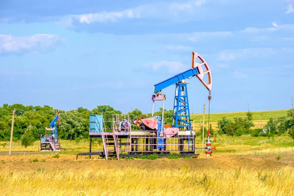 Silla mecedora para extracción de aceite en la árida estepa en un día soleado contra el cielo azul. Producción industrial de petróleo. — Foto de Stock