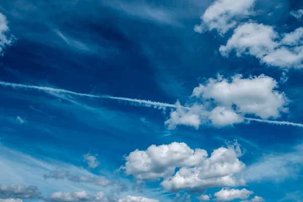 White clouds and haze against the blue sky. Condensation trail from an airplane flying at high altitude. Trail of water vapor and ice crystals.