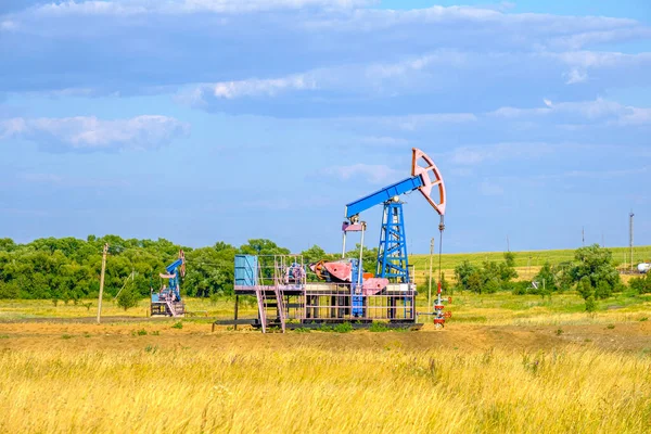 Silla mecedora para extracción de aceite en la árida estepa en un día soleado contra el cielo azul. Producción industrial de petróleo. — Foto de Stock