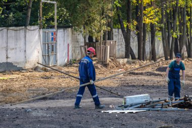 Moskova. - Rusya. İnşaat alanında üniformalı ve kasklı inşaat işçileri, inşaat malzemelerini elle transfer ediyorlar. Yaz günü. İnşaat endüstrisi