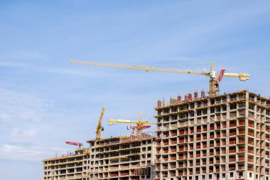 Moskova. - Rusya. 06 Eylül 2020 'de gökyüzünün arka planına karşı modern bir monolitik ev inşaatının görüntüsü. Yüksek katlı bir apartmanın inşaatında kule vinçleri