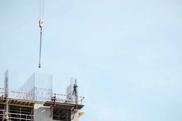 Moscow. Russia. September 06, 2020 View of the construction of a monolithic house against the background of the sky. A tower crane and uniformed workers assembling a reinforcing steel structure — Stock Image Moscow. Russia. September 06, 2020 View of the construction of a monolithic house against the background of the sky. A tower crane and uniformed workers assembling a reinforcing steel structure Stock Photo