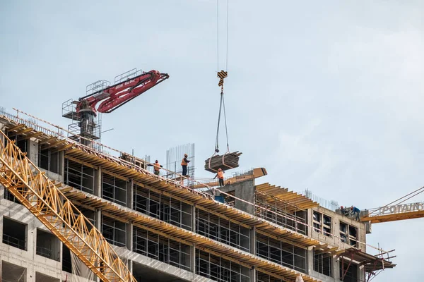 Moscow. Russia. September 06, 2020 View of the construction of a monolithic house against the background of the sky. A tower crane and uniformed workers assembling a reinforcing steel structure — Stock Image Moscow. Russia. September 06, 2020 View of the construction of a monolithic house against the background of the sky. A tower crane and uniformed workers assembling a reinforcing steel structure Stock Picture
