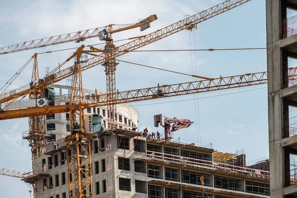 Moscow. Russia. September 06, 2020 View of the construction of a monolithic house against the background of the sky. A tower crane and uniformed workers assembling a reinforcing steel structure — Stock Image Moscow. Russia. September 06, 2020 View of the construction of a monolithic house against the background of the sky. A tower crane and uniformed workers assembling a reinforcing steel structure Stock Photo