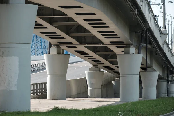 Bottom view of the concrete piers of the transport viaduct. Massive columns support the road bridge. Sunny day — Stock Photo, Image