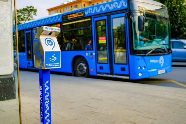 Moskau. Russland. 4. September 2020 Ein Gerät zur kontaktlosen Händedesinfektion an einer Haltestelle des öffentlichen Nahverkehrs vor einem blauen Stadtbus. Moderne Technologien, die Menschen vor Infektionen schützen — Stockfoto