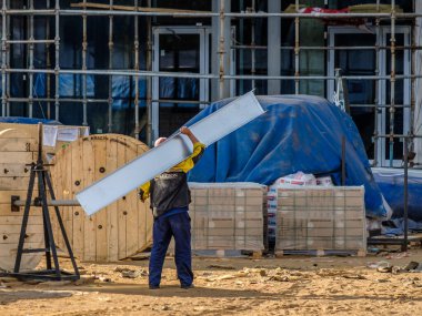 Moskova. - Rusya. İnşaat alanında üniformalı ve kasklı inşaat işçileri, inşaat malzemelerini elle transfer ediyorlar. Yaz günü. İnşaat endüstrisi