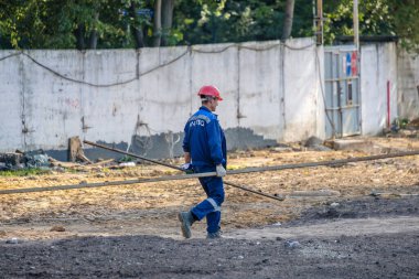 Moskova. - Rusya. İnşaat alanında üniformalı ve kasklı inşaat işçileri, inşaat malzemelerini elle transfer ediyorlar. Yaz günü. İnşaat endüstrisi
