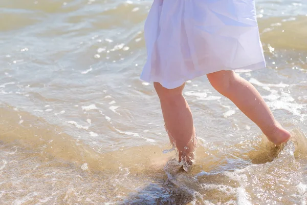 Małe nóżki z bliska na piasku morskiej plaży. Woda morska myje stopy. Szczęśliwego dzieciństwa. Odpocznij nad morzem. Letni słoneczny dzień. Przestrzeń kopiowania — Zdjęcie stockowe