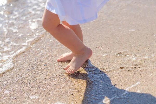 Baby piedi primo piano sulla sabbia della spiaggia del mare. L'acqua di mare lava i piedi. Buona infanzia. Riposa al mare. Giornata estiva di sole. Copia spazio — Foto Stock