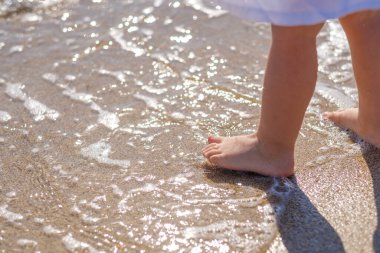 Yavru ayaklar deniz sahilinin kumsalına yakın çekim. Deniz suyu ayaklarını yıkar. Mutlu bir çocukluk. Denizde dinlen. Yaz güneşli bir gün. Boşluğu kopyala