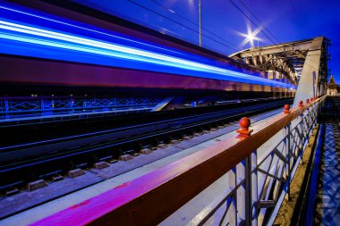 Hızlı bir trenden gelen bulanık ışık çizgileri. Tren gece vakti demiryolu köprüsünün kemerlerinden geçer.. 
