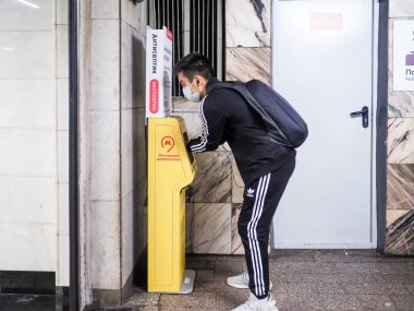 Moskova. - Rusya. 22 Eylül 2020. Bir yolcu Moskova metro istasyonunda antiseptikle ellerini özel bir otomatikle tedavi ediyor. Viral enfeksiyonların yayılmasını önlemek için devlet tedbirleri.