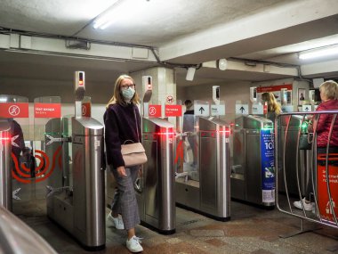 Moskova. - Rusya. 22 Eylül 2020. Yolcular Moskova metro istasyonundaki otomatik turnikelerden geçiyorlar. İnsanların yüzlerinde enfeksiyonlara karşı koruyucu maskeler ve viral enfeksiyonların yayılması