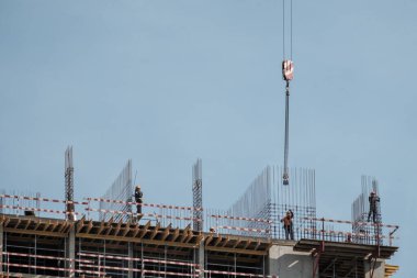 Moskova. - Rusya. 06 Eylül 2020 'de gökyüzünün arka planına karşı monolitik bir ev inşa edilişi. Kule vinci ve üniformalı işçiler güçlendiren çelik bir yapı oluşturuyorlar..