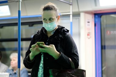 Moskova. - Rusya. 25 Eylül 2020 metro vagonunda genç bir kadın akıllı telefon tutuyor. Yolcuların yüzlerinde koruyucu maskeler var. Toplu taşımacılıktaki viral enfeksiyonlara karşı koruma.