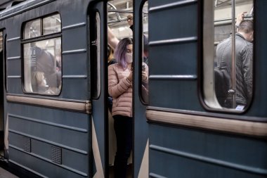 Moskova. - Rusya. 28 Eylül 2020. Metro vagonunda genç bir kadın. Yolcunun yüzünde koruyucu bir tıbbi maske var. Viral enfeksiyon önleme önlemleri. Toplu taşımacılıkta sosyal uzaklık.