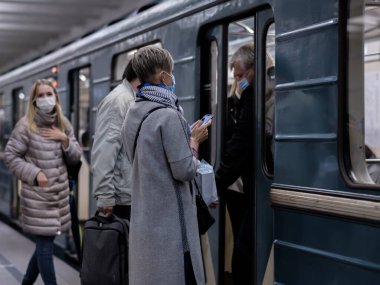 Moskova. - Rusya. 28 Eylül 2020. Koruyucu maskeli genç bir kız metro istasyonunun platformunda duruyor ve bir akıllı telefona coşkuyla bakıyor. Tren vagonları yakınlarda duruyor.. 