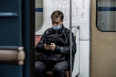 Moskova. - Rusya. 28 Eylül 2020 'de metro vagonunda bir adam telefonuna hevesle bakıyor. Yolcunun yüzünde koruyucu bir tıbbi maske var. Koronavirüsün ikinci dalgası.