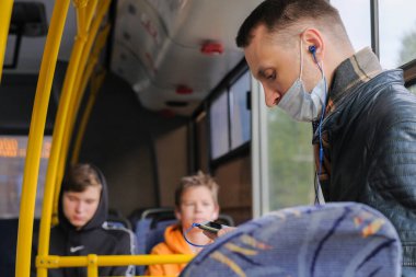 Moskova. - Rusya. 29 Eylül 2020. Otobüsteki genç bir adam kulaklıkla müzik dinliyor. Yolcunun yüzünde koruyucu bir maske var. Koronavirüs salgınının ikinci dalgası..