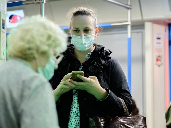 Moskova. - Rusya. 25 Eylül 2020 metro vagonunda genç bir kadın akıllı telefon tutuyor. Yolcuların yüzlerinde koruyucu maskeler var. Toplu taşımacılıktaki viral enfeksiyonlara karşı koruma.