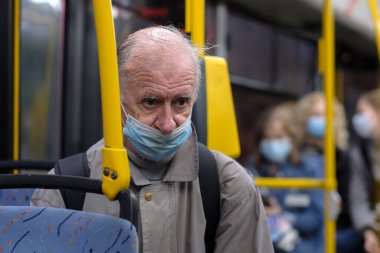 Moskova. - Rusya. 24 Eylül 2020. Şehir otobüsünde yıpranmış koruyucu maske takan yaşlı, kır saçlı bir adam. Viral enfeksiyon önleme önlemleri. Toplu taşımacılıkta sosyal uzaklık.