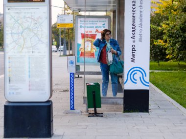 Moskova. - Rusya. 25 Eylül 2020. Yetişkin bir kadın otobüs beklerken toplu taşıma köşkünde duruyor. Bir kadın elinde tıbbi bir maske tutuyor. Koronavirüsün ikinci dalgası.