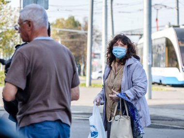 Moskova. - Rusya. 4 Ekim 2020. Koruyucu tıbbi maskeli yetişkin bir kadın otobüs durağında otobüs bekliyor..