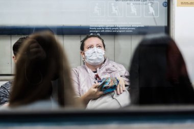 Moskova. - Rusya. 25 Eylül 2020 'de metro vagonunda koruyucu maskeli genç bir kadın akıllı telefon tutuyor..