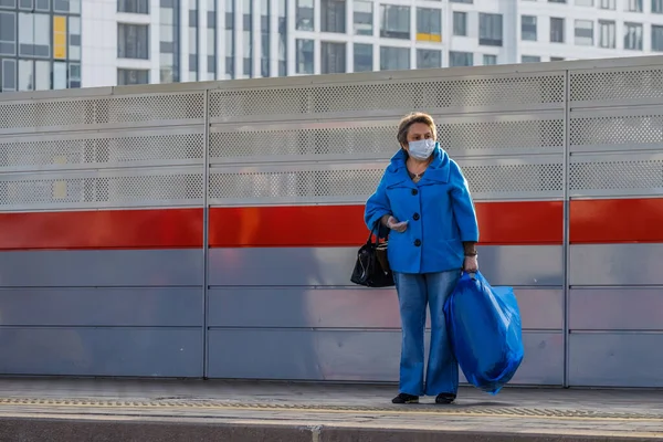 В Москве. Россия. 4 октября 2020 года. Взрослая женщина в защитной медицинской маске стоит на платформе станции метро — стоковое фото