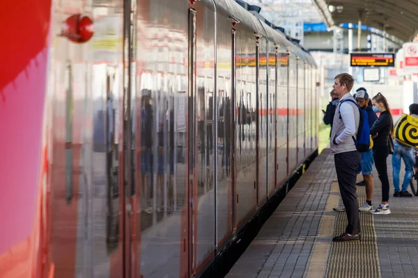 Москва. Росія. 4 жовтня 2020. Молодий чоловік серед інших пасажирів стоїть на платформі залізничного вокзалу. — стокове фото