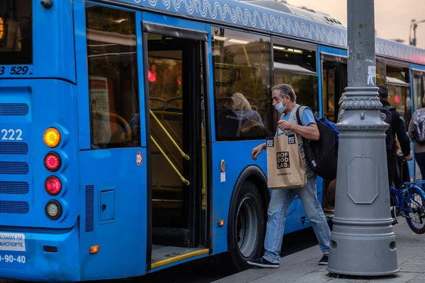 Moskau. Russland. Am 25. September 2020 schreitet ein Mann mit einer medizinischen Maske an einem Tag durch die offenen Türen eines Busses. — Stockfoto