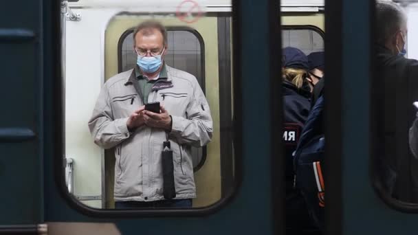 Moskau. Russland. 8. Oktober 2020 Ein Mann in einem U-Bahn-Wagen mit Schutzmaske im Gesicht hält ein Smartphone in der Hand. — Stockvideo