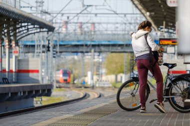 Moskova. - Rusya. 4 Ekim 2020 Bisikletli ve sırt çantalı genç bir kız tren istasyonunun peronunda duruyor.