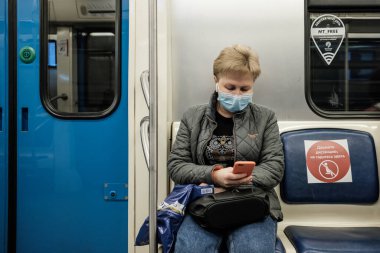 Moskova. - Rusya. 5 Ekim 2020. Metro vagonundaki yetişkin bir kadın akıllı telefon tutuyor..