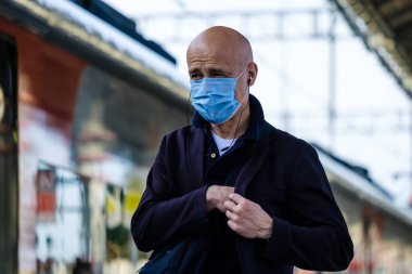 Moskova. - Rusya. 4 Ekim 2020. Koruyucu tıbbi maskeli ve kulaklıklı yalnız kel bir adam tren yolunda yürüyor.
