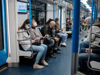 Moskova. - Rusya. 5 Ekim 2020 'de metro vagonunda koruyucu maskeli genç bir kadın akıllı telefon tutuyor..
