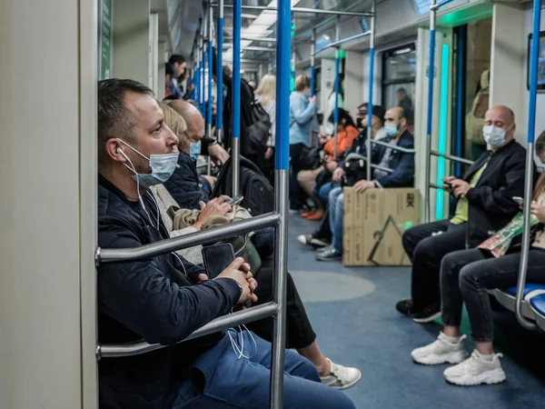Mosca. Russia. ottobre 5, 2020 Un uomo in un vagone della metropolitana con uno smartphone ascolta musica con le cuffie. — Foto Stock