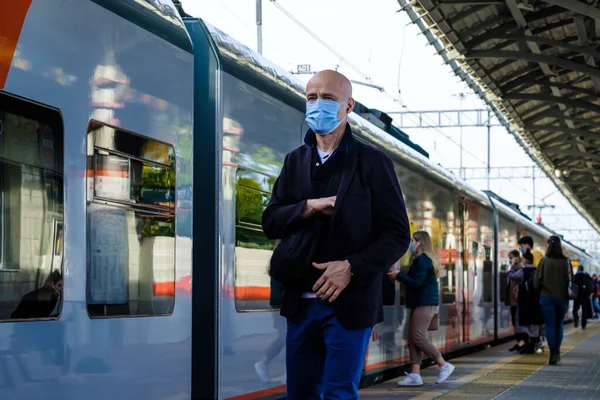 Moskova. - Rusya. 4 Ekim 2020. Koruyucu tıbbi maskeli ve kulaklıklı yalnız kel bir adam tren yolunda yürüyor.