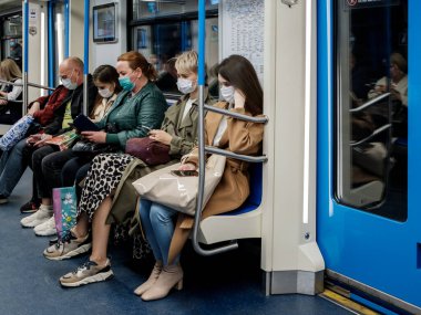 Moskova. - Rusya. 5 Ekim 2020. Yüzünde koruyucu maske olan genç bir kadın metro vagonunda duruyor..