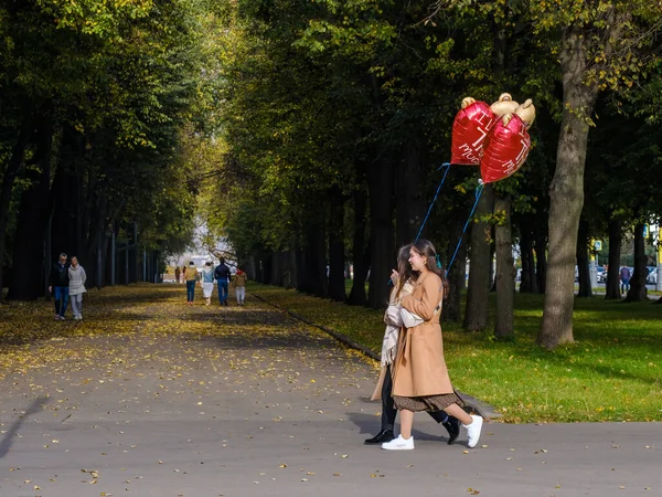 Moscovo. A Rússia. 11 de Outubro. Casal feliz de meninas apaixonadas com bolas vermelhas em uma data em um parque da cidade em um dia ensolarado outono — Fotografia de Stock