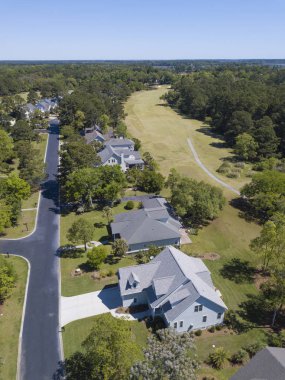 High angle aerial view of houses along golf course in planned community. clipart
