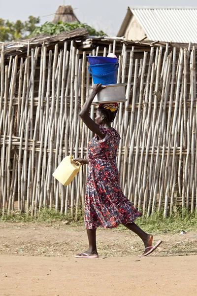 Vrouw met spullen op hoofd in Afrika — Stockfoto