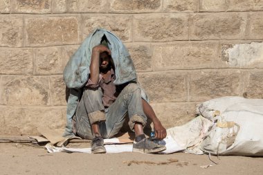 Addis Ababa, Etiyopya - Circa Kasım, 2014: Gün ışığından taş duvarla saklanan yerel adam