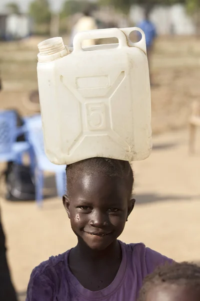Dítě vezující vodu na hlavu v jižním Súdánu — Stock fotografie