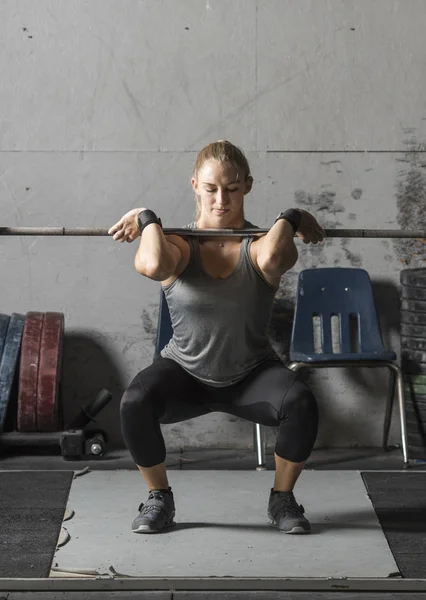 Mujer joven levantador de pesas haciendo sentadillas en el gimnasio gruñón, primer plano sho —  Fotos de Stock
